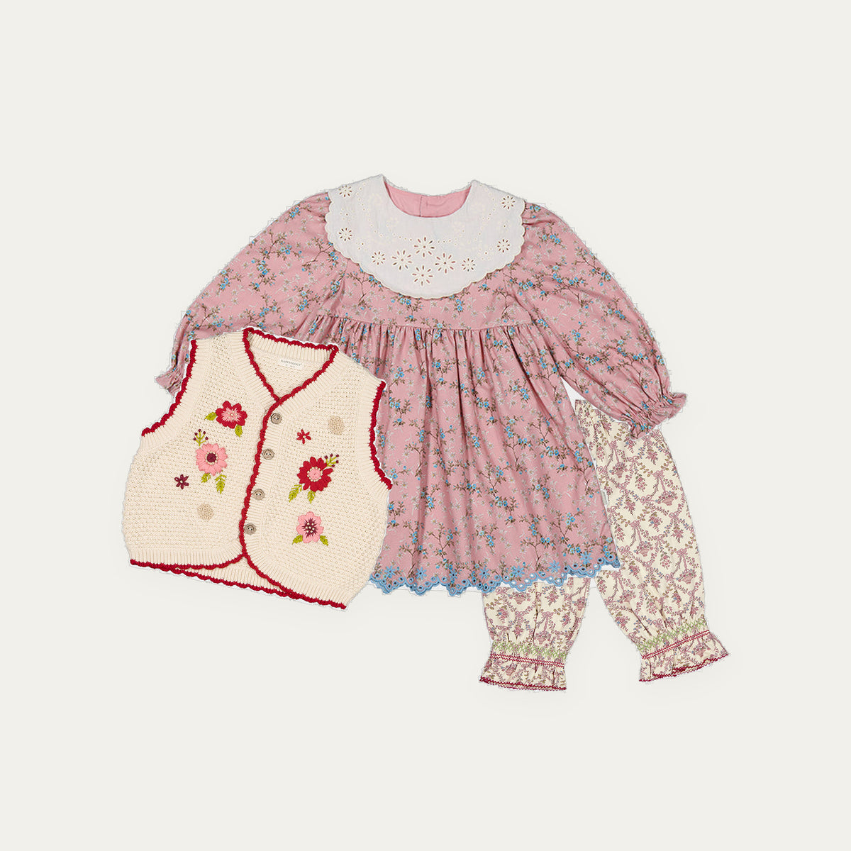 Happyology Lucky Bag, three autumn winter sample pieces laid out - embroidered dress, knitted vest and floral trousers